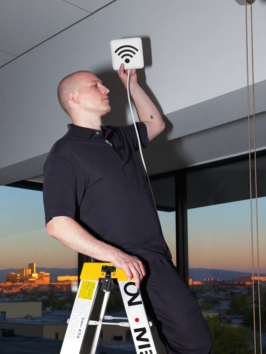 Technicus monteert een wifi-accesspoint aan het plafond